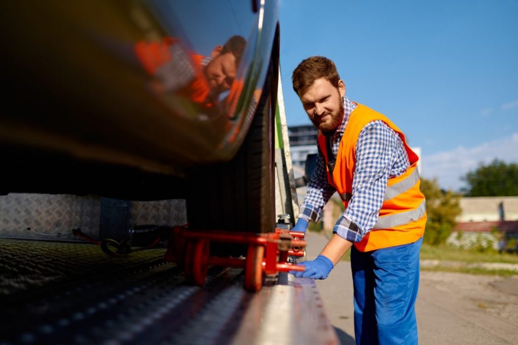 RecNow Recovery operator securing a vehicle onto the tow truck flatbed platform